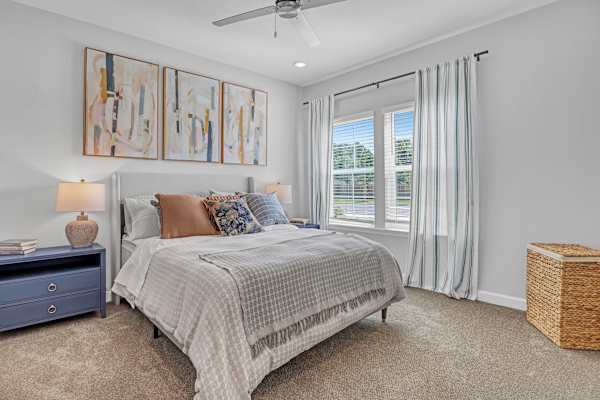 A bedroom with a bed, nightstand, and a painting on the wall.